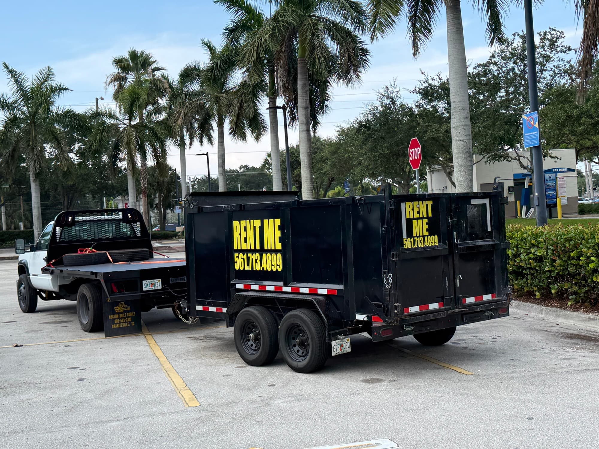 Safe USA Transport dump trailer with RENT ME 561.713.4899 signage hitched to a pickup truck